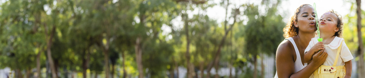 Madre e hijo soplando burbujas en el parque 