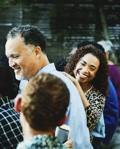 Laughing woman in discussion with family member during outdoor family dinner party