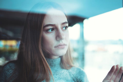 Woman looking outside window mental health