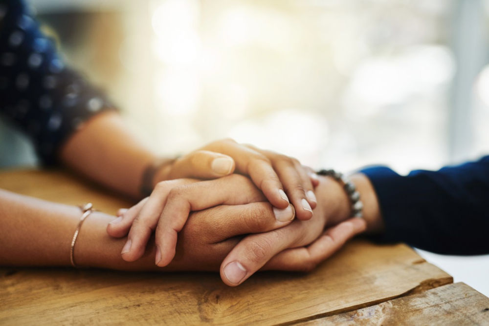 Primer plano de dos personas irreconocibles que se toman de la mano con comodidad