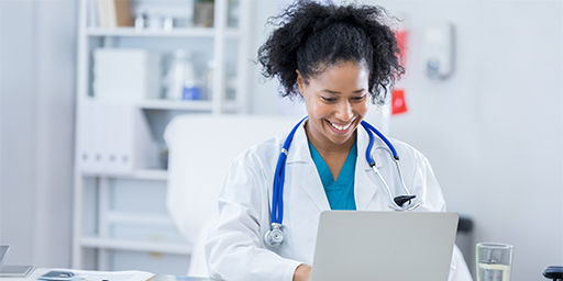 Cheerful  doctor uses a laptop in her office