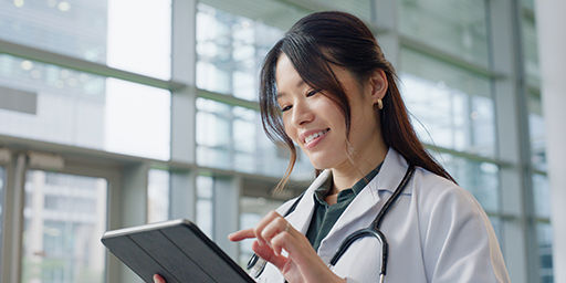 Asian woman, doctor and happy in hospital with tablet for public service, results and committed. Female person, closeup and smile for healthcare with appointment, work and wellness in medical career