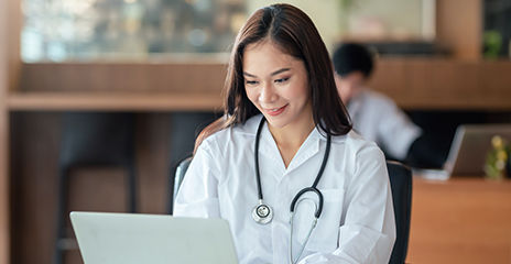 doctor smiling and using laptop computer on work table.