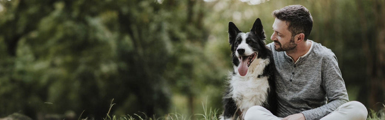 man sittng with dog on grass