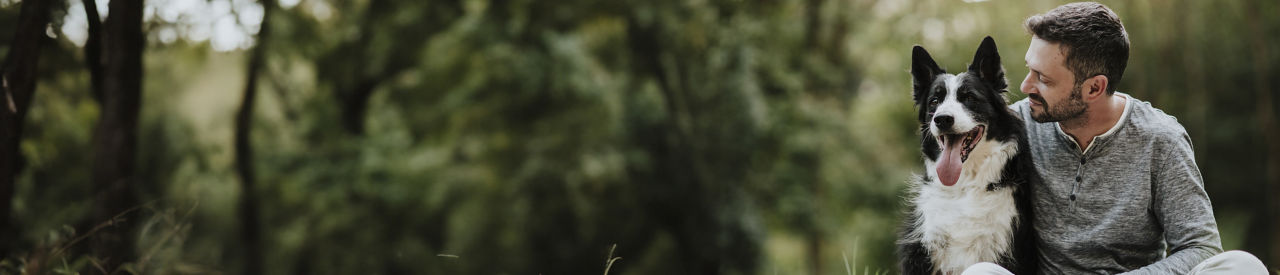 hombre sentado con un perro en el césped