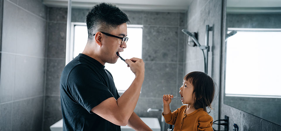 father and daughter brushing teeth