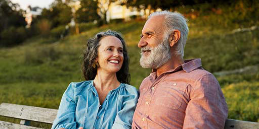 senior couple happy and talking on bench outside