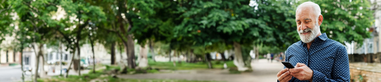 hombre mayor en el parque revisando su teléfono móvil