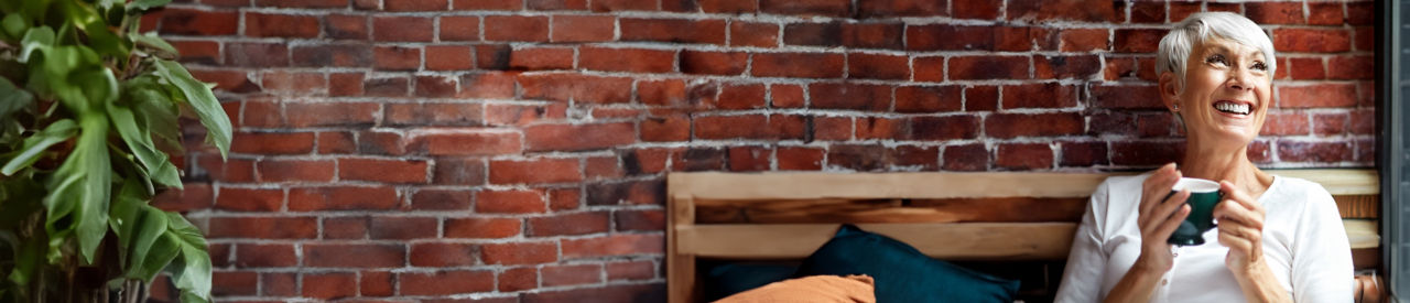 Senior woman drinking coffee while looking out a window.