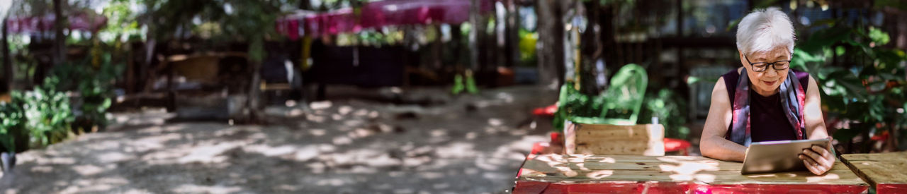 Asian  Senior Woman Using Digital Tablet outdoors.