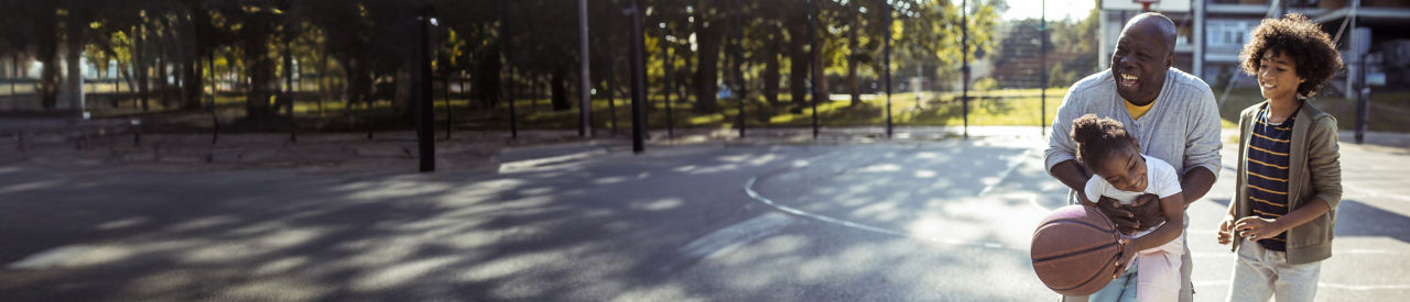 senior playing basketball outside with young kids