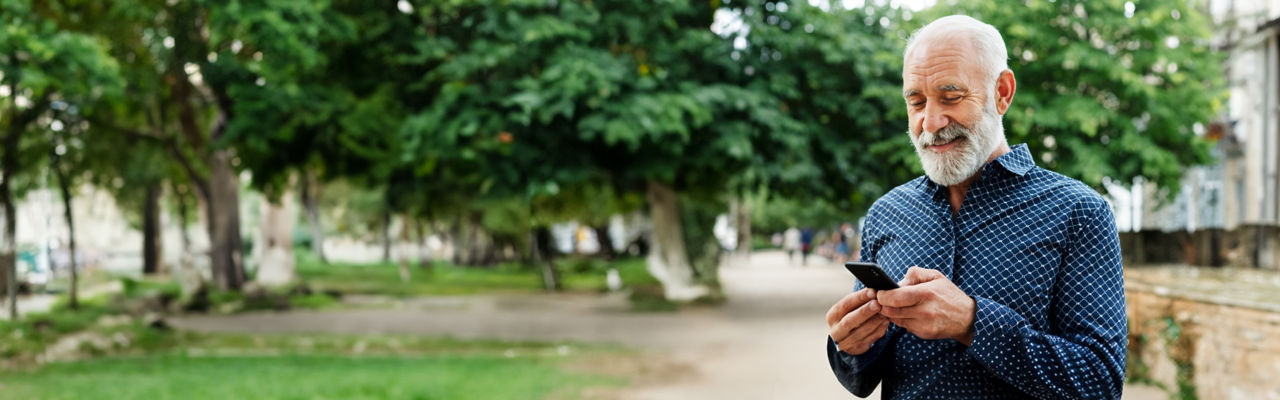 Senior man at the park checking his mobile phone.