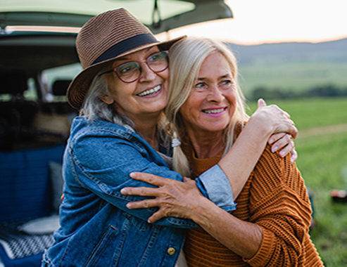 Old women standing by car, hugging.