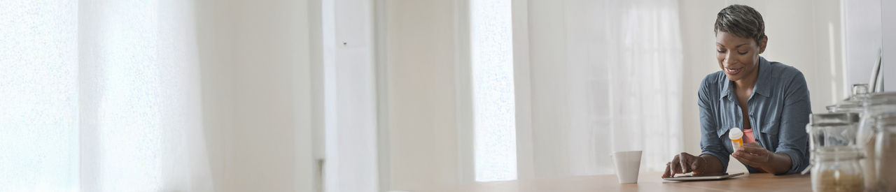 Mujer tomando medicamentos en la cocina de su casa