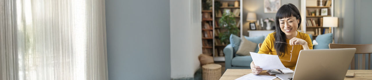 person on laptop and holding a document at home