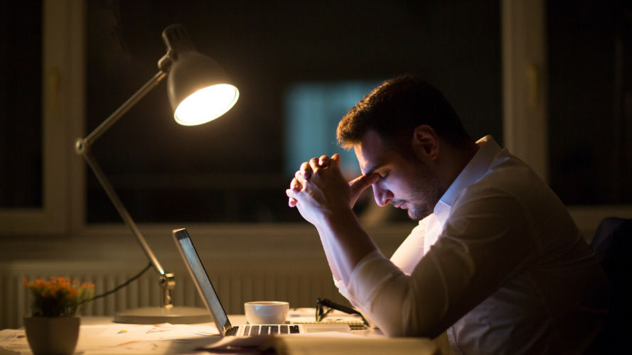 Man sitting at office desk dealing with mental stress