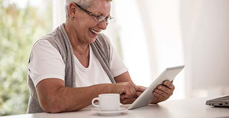 happy senior watching tablet at home