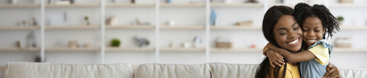 mother hugging young daughter on couch at home