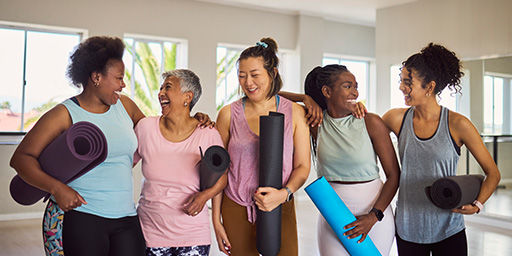 mujer en un grupo de cinco personas riendo y sonriendo antes de una clase de yoga
