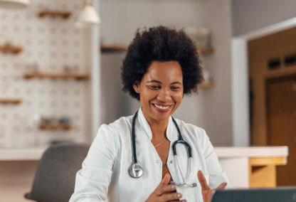 Young female doctor smiling and looking at laptop