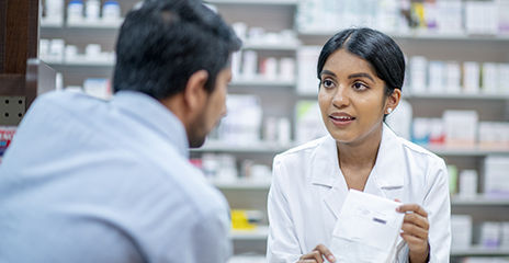 pharmacist talking to customer about his prescription.