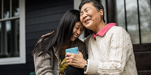 senior mother and daughter sitting on bench outdoors and smiling