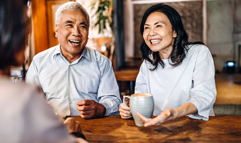 Pareja en una mesa hablando con un invitado