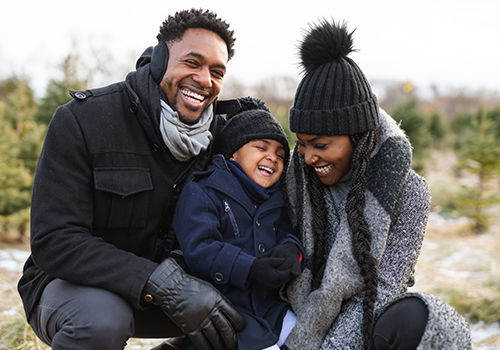 A beautiful family laugh together as they have their family laughing together outside in cold weather.