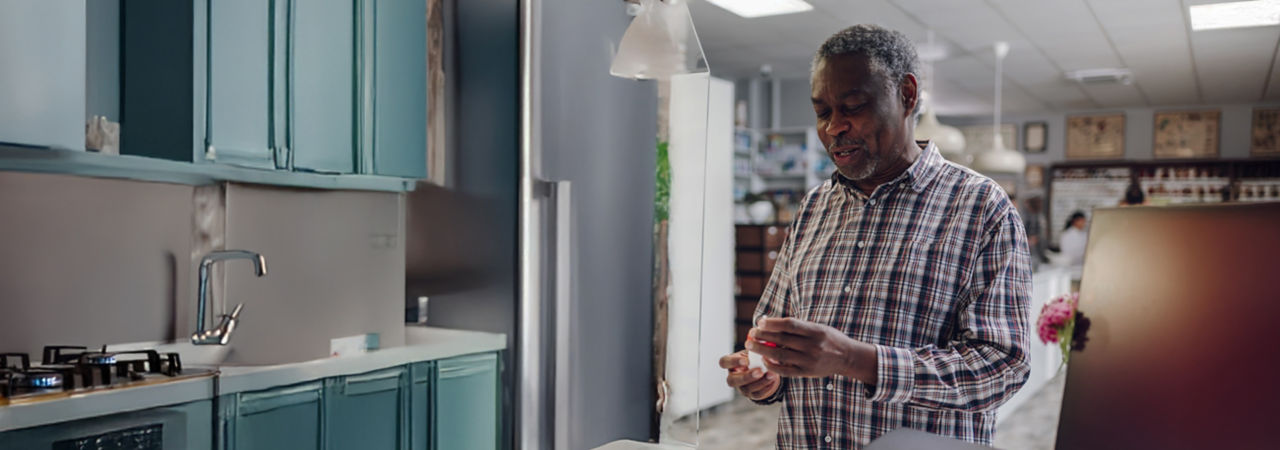 man using diabetes monitor in kitchen