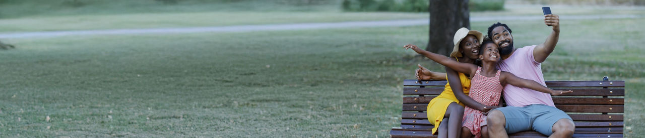 family of three taking a selfie on a park bench