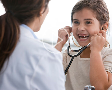 doctor with smiling child trying on stethoscope