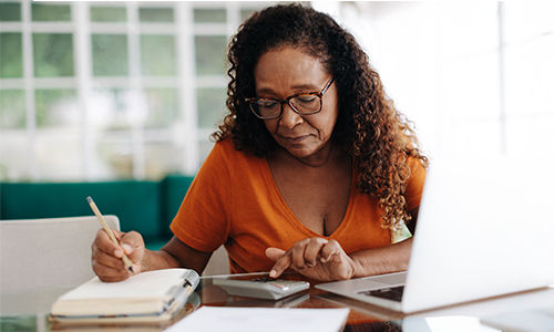 Senior woman making calculations at desk