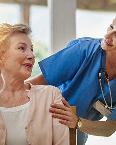 Shot of a smiling senior woman talking with a nurse in assisted living facility