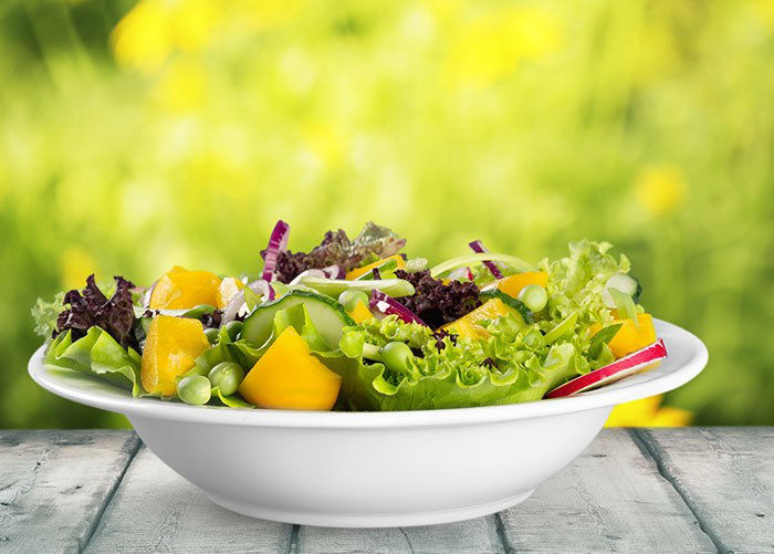 Spinach salad in a white bowl.