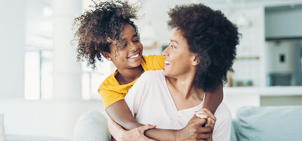 Happy African ethnicity mother and daughter at home