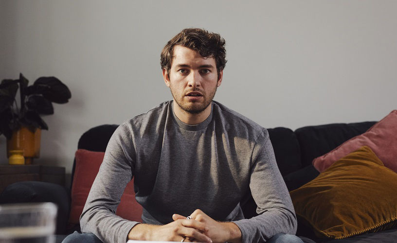 Portrait of young white man with beard, looking towards camera, he looks worried.