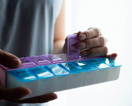 Primer plano de las manos de una mujer sosteniendo un pastillero