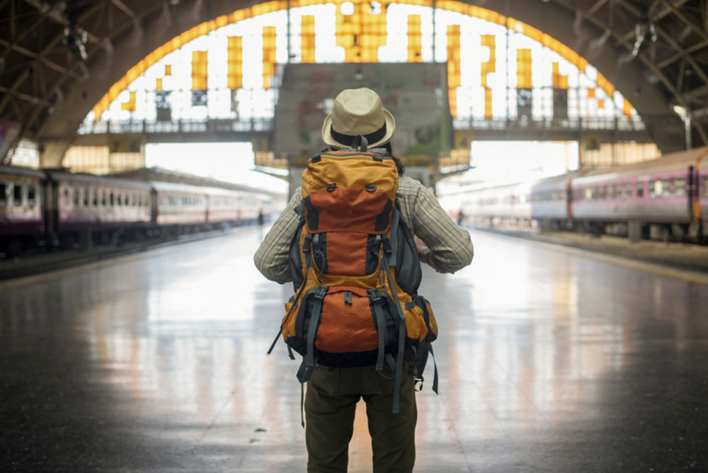 Hombre viajero espera tren en la plataforma ferroviaria.