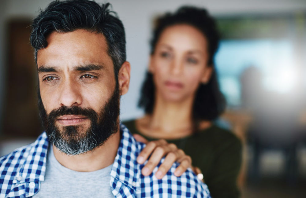 Foto de una mujer consolando a su esposo angustiado en casa