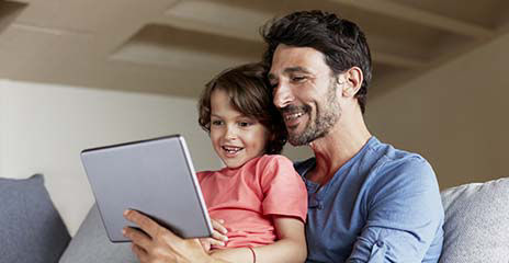 Happy father and son using digital tablet on sofa at home