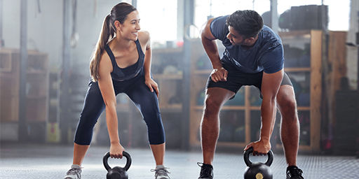 dos adultos jóvenes entrenando en el gimnasio