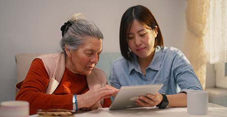 senior female and young adult looking at tablet