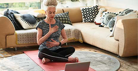 Una mujer mayor hace meditación virtual en casa