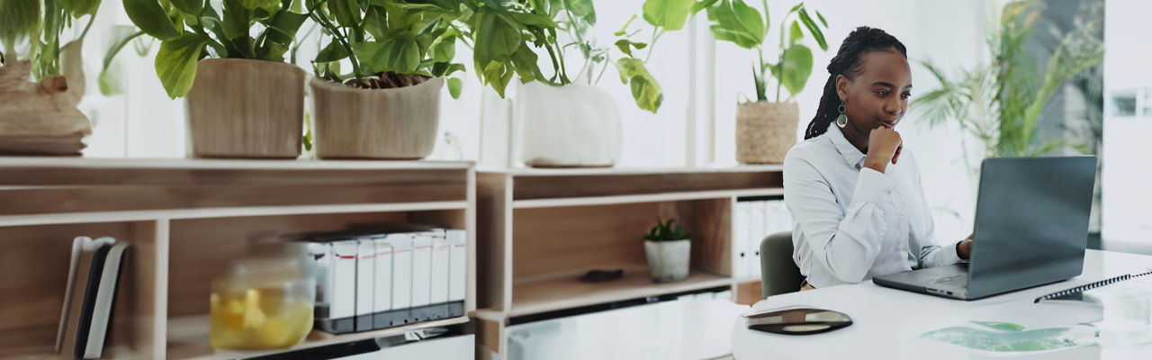 person sitting at laptop in room with plants