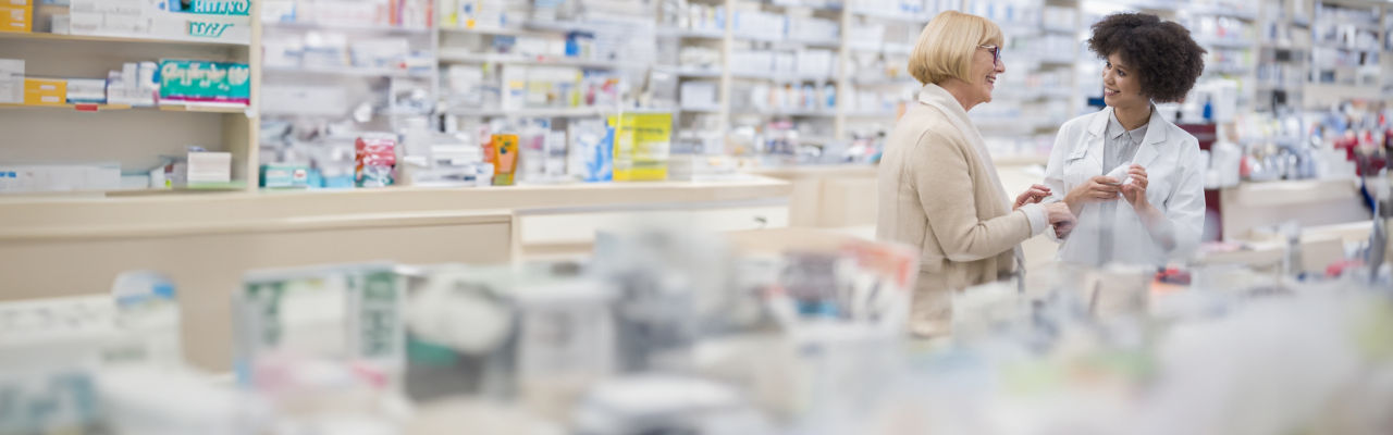 Mujer joven ayuda a una mujer mayor en la farmacia