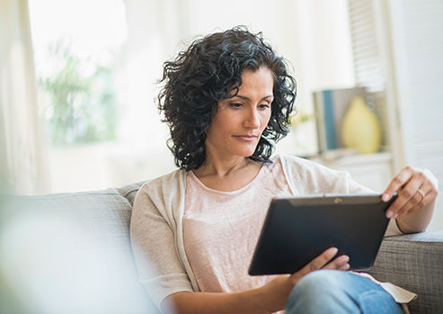 Mujer que usa una tableta digital sobre el sofá