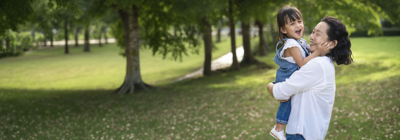 senior holding grandchild in park