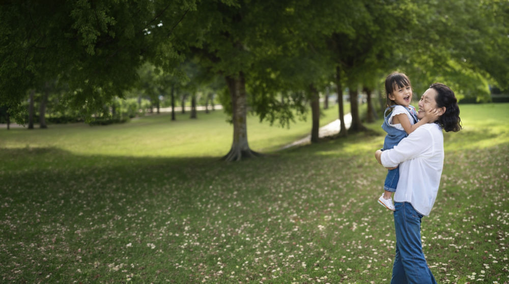 senior holding grandchild in park